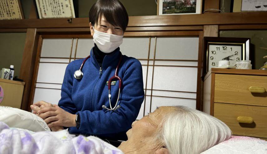 ベッドに横たわる高齢者をと話している様子